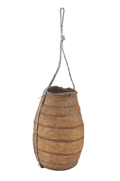 Dicht geflochtenes Korb-Gefäß mit Tragschlaufe. Der Rand ist mit einer Umwicklung aus Leder verstärkt. Das Gefäß ist Naturfarben, mit dunklen Querstreifen.