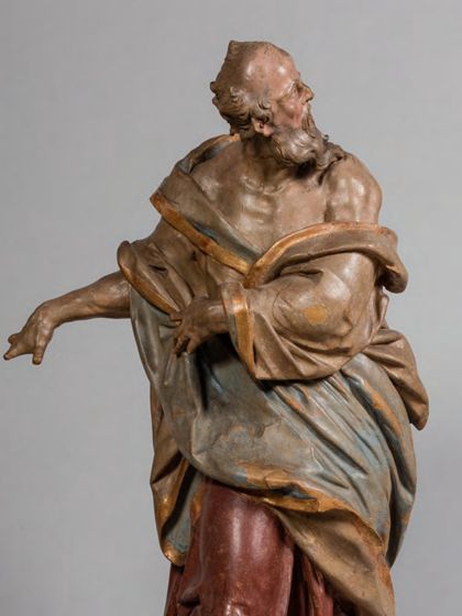 Stehende Holzskulptur des Apostels Simon Zelotes in theatralisch verdrehter Körperhaltung und ebenso expressiver Drapierung des stoffreichen Gewands, Detail des Oberkörpers.