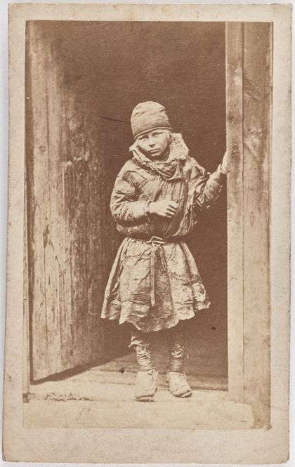 Fotografie eines sámischen Kindes, das in einem Türrahmen steht.