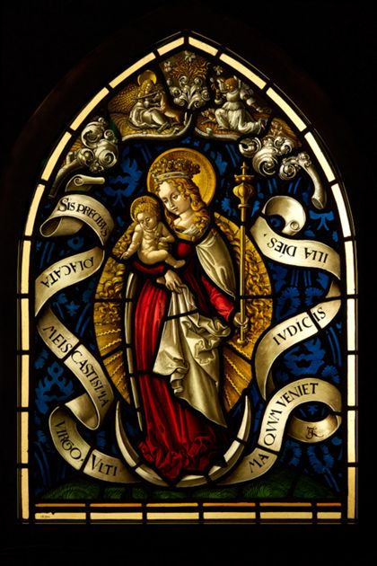 Spitzbogiges Kirchenfenster mit der Darstellung der Muttergottes im Strahlenkranz auf einer Mondsichel.