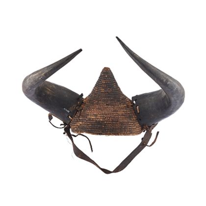 Aus Pflanzenfasern geflochtener Helm. Seitlich sind mittels Lederstreifen zwei Büffelhörner befestigt. Das Kinnband ist aus Leder.