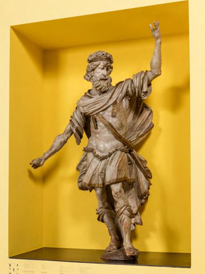 Überlebensgroße, monochrom hell gefasste Skulptur des Samson als Kanzelträger in römisch-antiker Soldatenbekleidung, seitliche Ansicht.