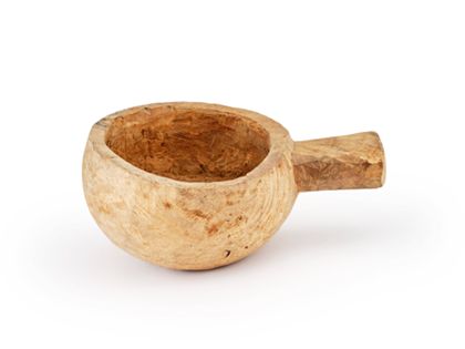 Eine kreisrunde Melkschale mit kurzem Griff aus hellem Holz.