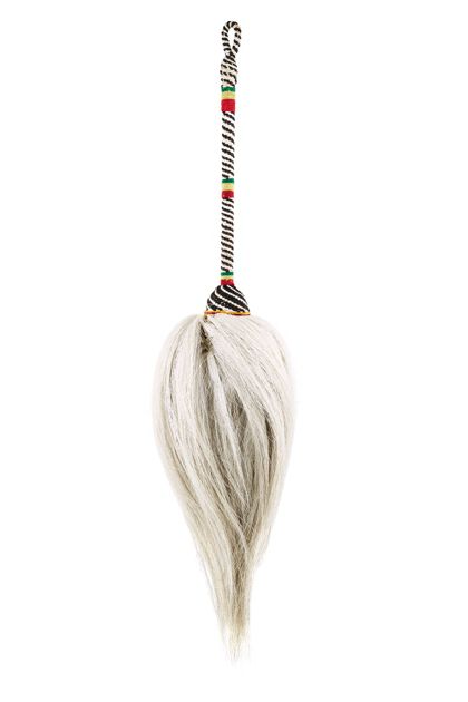 Wedel aus weißem Haar. Der Stiel ist mit schwarzem, weißem, rotem, grünem und gelbem Faden umwickelt, so dass sich ein schwarz-weißes Muster mit Untersetzungen in rot, gelb und grün ergibt.